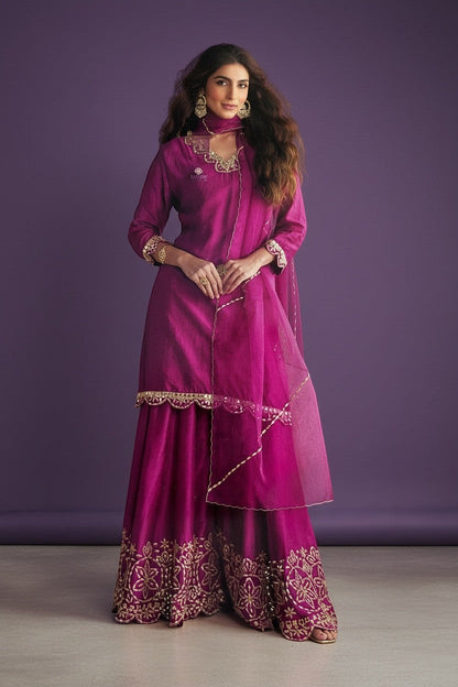 Kurti Connection USA magenta silk sharara suit with gold embroidery and sheer dupatta. Model wears ornate earrings and bracelet.